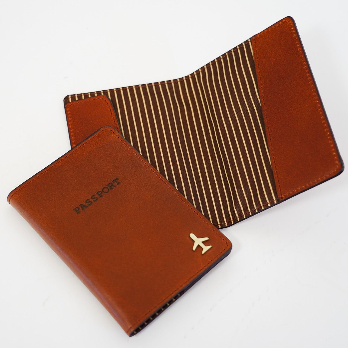Two brown leather travel passport holders with a visible brand logo on a white background