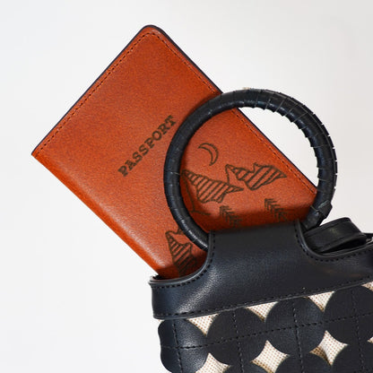 Black and white patterned handbag with a brown leather passport holder on a white background