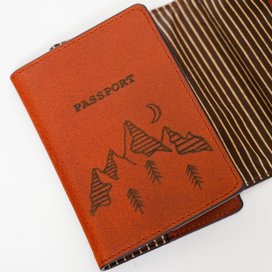 Brown passport holder with mountain design on a white background