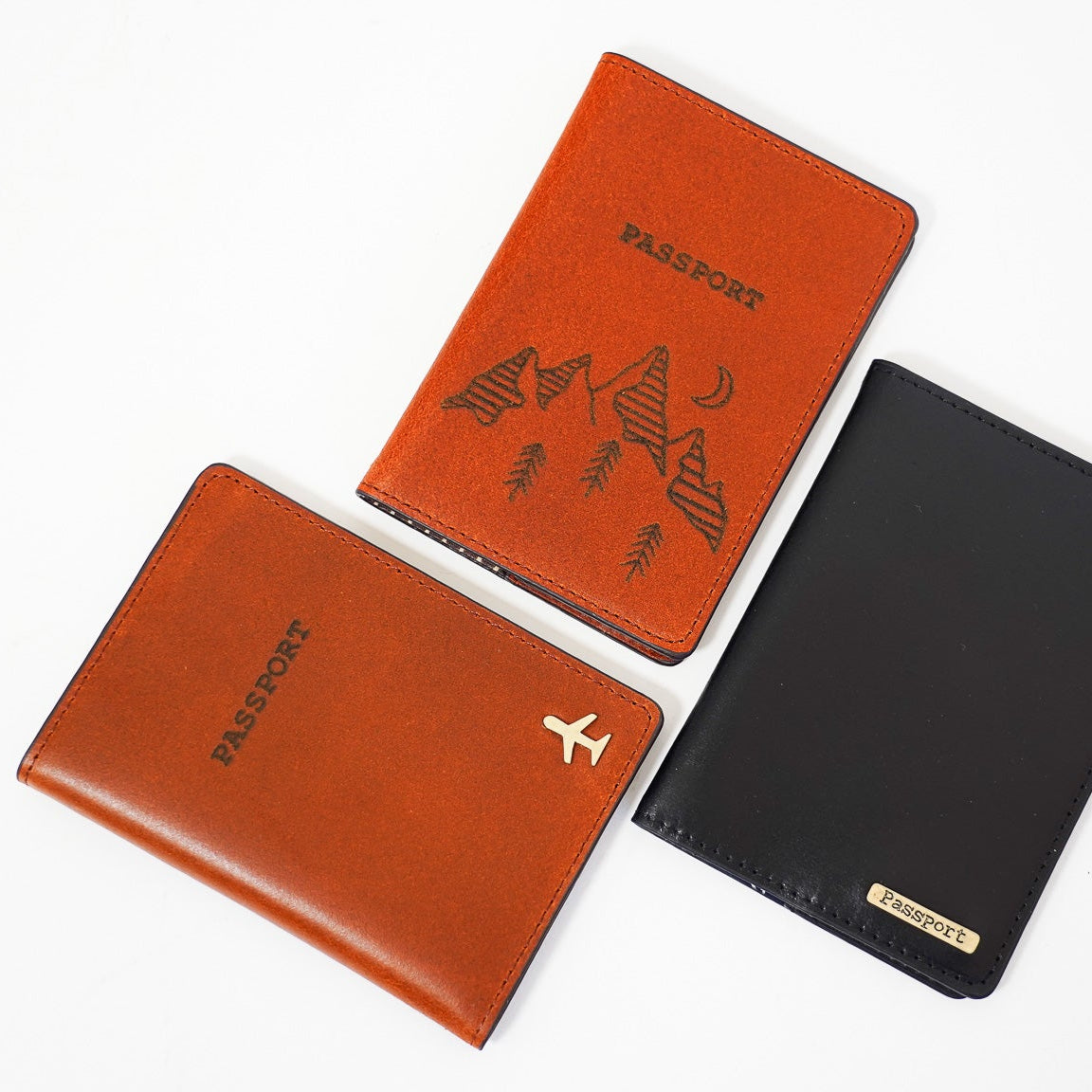 Three passport holders in orange, black, and brown on a white background